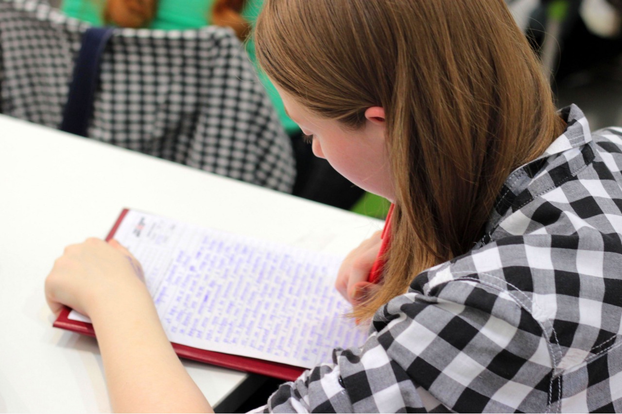 Estudante com camisa xadrez escrevendo redação no caderno
